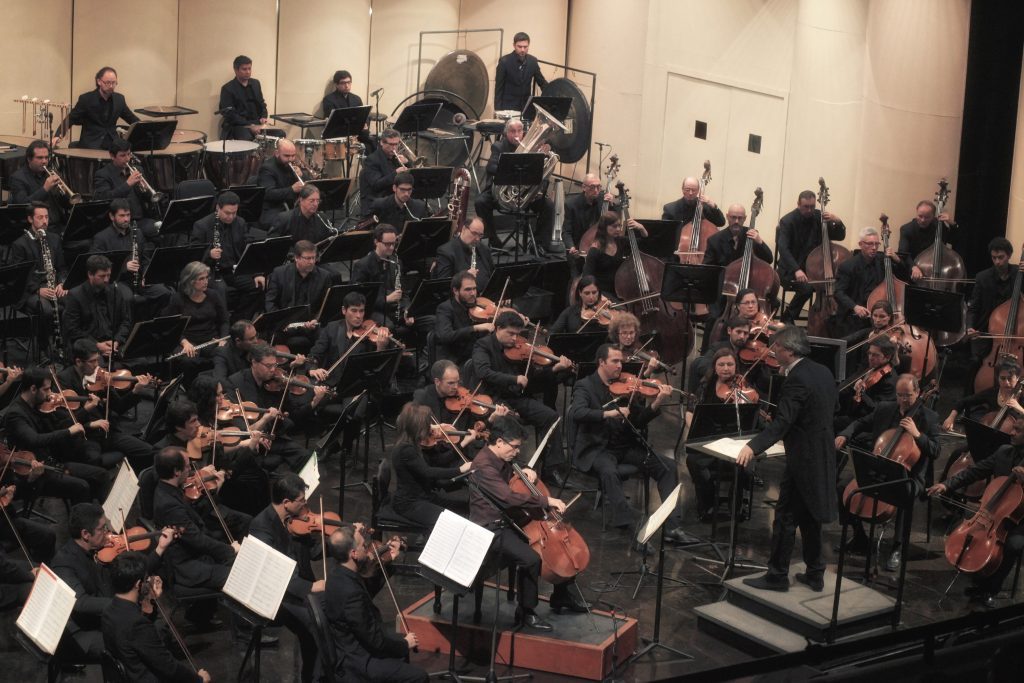 Concierto 12 del Ceac: La contemporaneidad romántica de un maestro holandés Orquesta Sinfónica Nacional en concierto, músicos con instrumentos de cuerda y dirección desde podio elevado