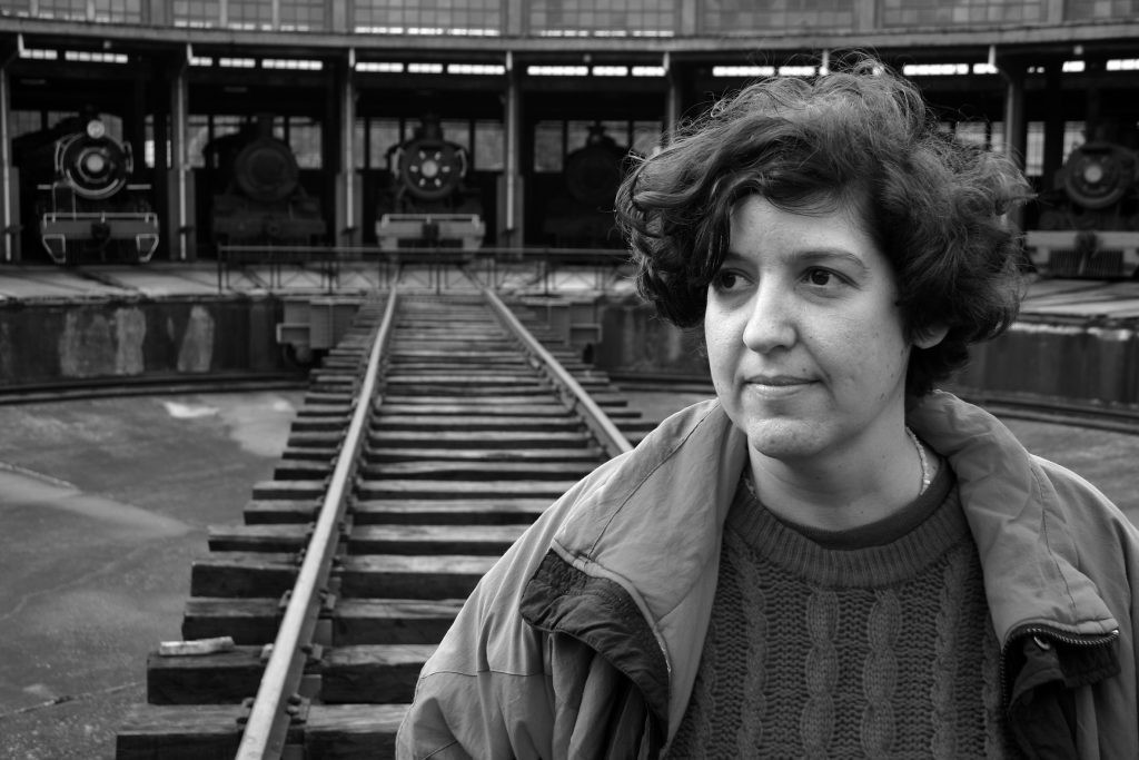 "Mi corazón es una trampa para osos", y otros: Poemas vírgenes de Damaris Calderón Retrato en blanco y negro de Damaris Calderón, poeta, junto a vías de tren en ambiente urbano