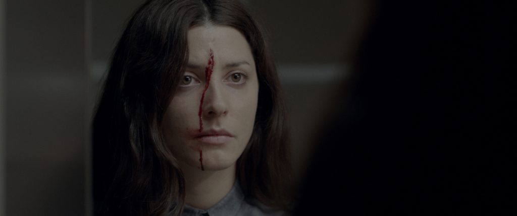 "El quinto elemento", el poemario detenido de Mirka Arriagada Bárbara Lennie con cabello largo negro, expresión seria, en escena de película con iluminación tenue