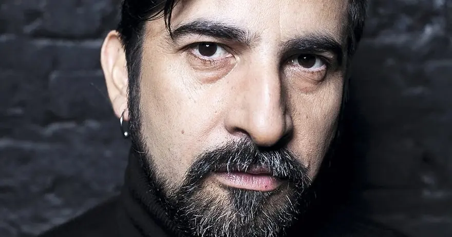 Roberto Farías, hombre de barba oscura y expresión seria, retrato en primer plano sobre fondo oscuro