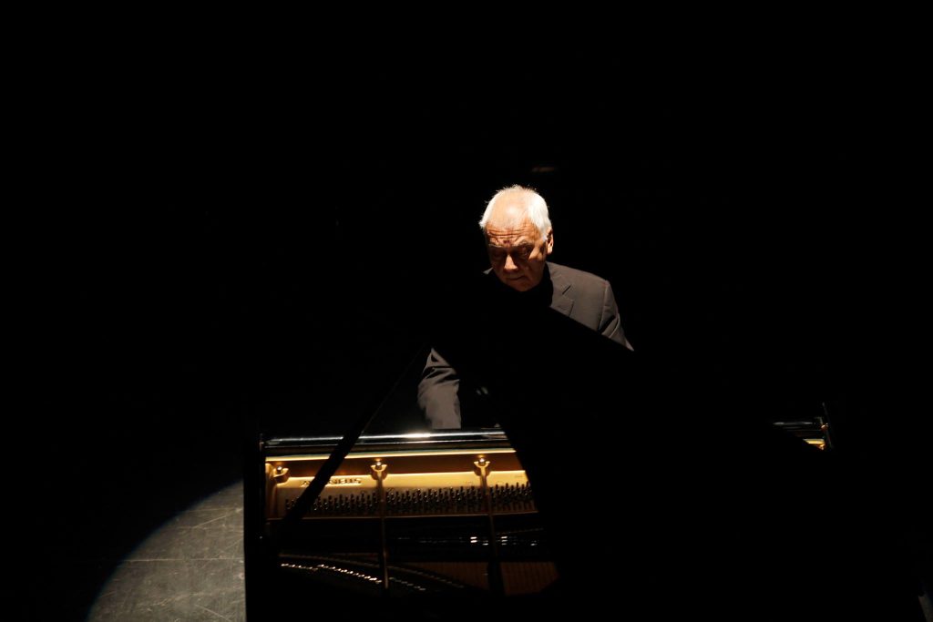 Pianista Jean Louis Steuerman concentrado en el teclado durante presentación en escenario oscuro