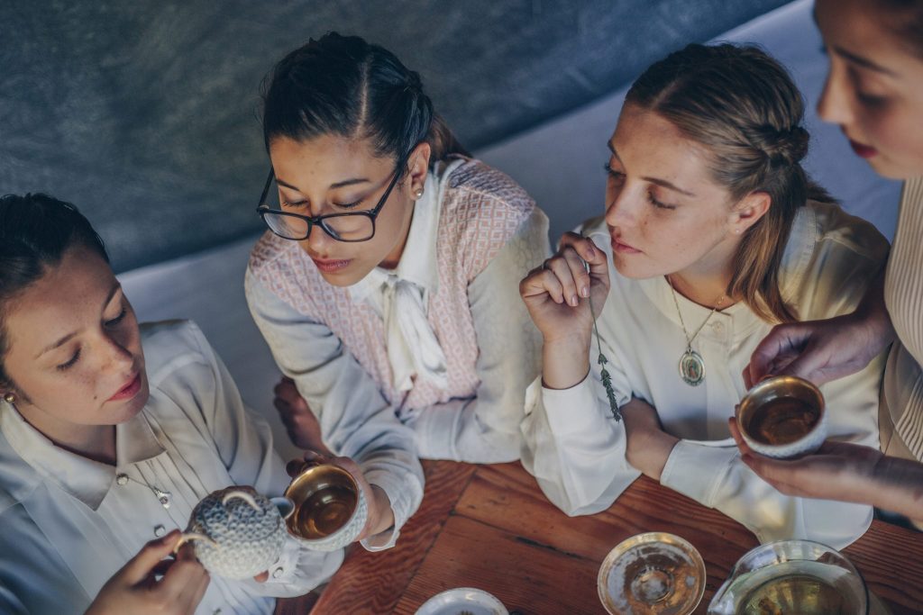 Cuatro jóvenes mujeres alrededor de una mesa compartiendo comida, en escena íntima de conexión y conversación