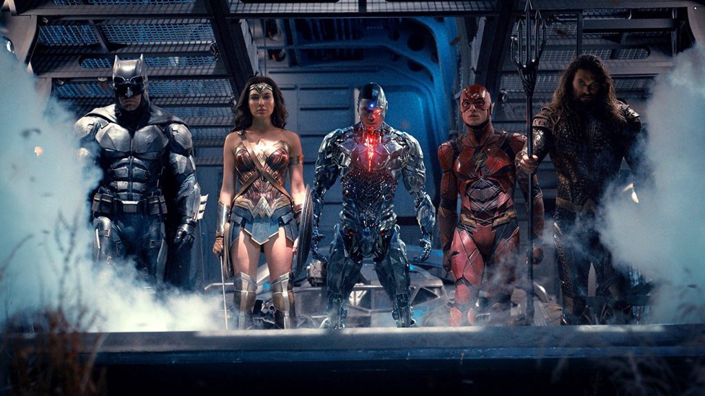 Cinco superhéroes en formación: Batman, Wonder Woman, Flash, Aquaman y Cyborg posando juntos entre efectos de luz azul