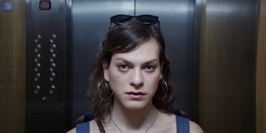 Mujer joven dentro de un ascensor, mirando directamente a cámara con expresión seria y contemplativa