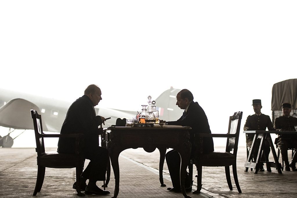 "Las horas más oscuras": Churchill solo frente a Hitler Dos hombres en silueta juegan ajedrez frente al mar, representando la estrategia política de Churchill ante Hitler
