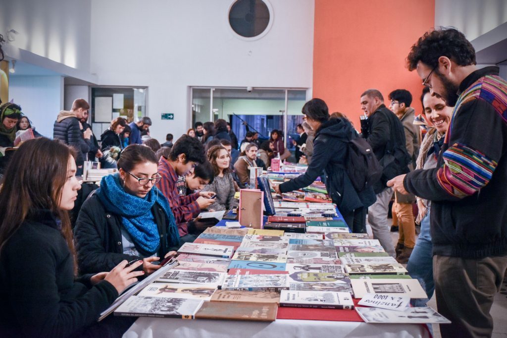 Visitantes y expositores en la Feria del Libro Independiente de Valparaíso, explorando publicaciones en mesas