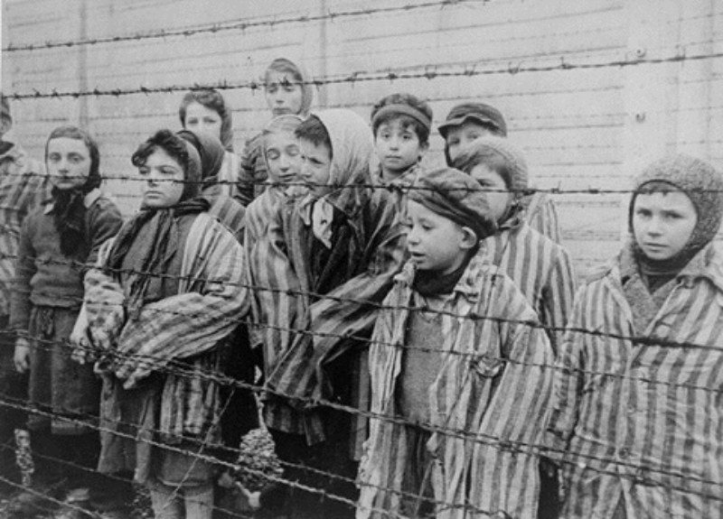 "El hombre en busca de sentido", de Viktor Frankl: Un rayo de luz de resiliente belleza Niños con uniformes de prisionero junto a cerca de alambre de púas en Auschwitz durante el Holocausto