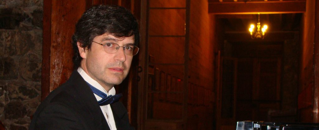 Felipe Browne, pianista chileno, de traje y corbata en interior elegante con iluminación cálida