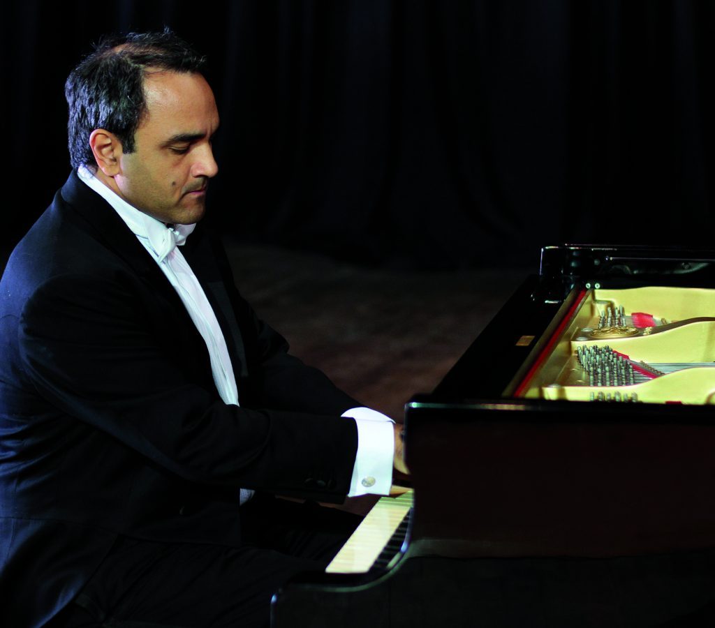 Pianista Daniel Barenboim en traje oscuro tocando piano de cola sobre fondo negro