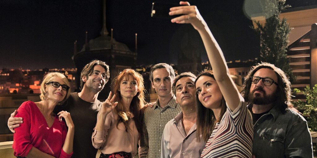 Grupo de amigos reunidos en la noche tomándose una selfie, con expresiones de diversión y complicidad en ambiente urbano
