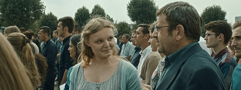 "Graduación", de Cristian Mungiu: Una construcción existencialista sobre el derrumbe Mujer rubia en primer plano durante una conversación en una multitud de personas en un espacio público