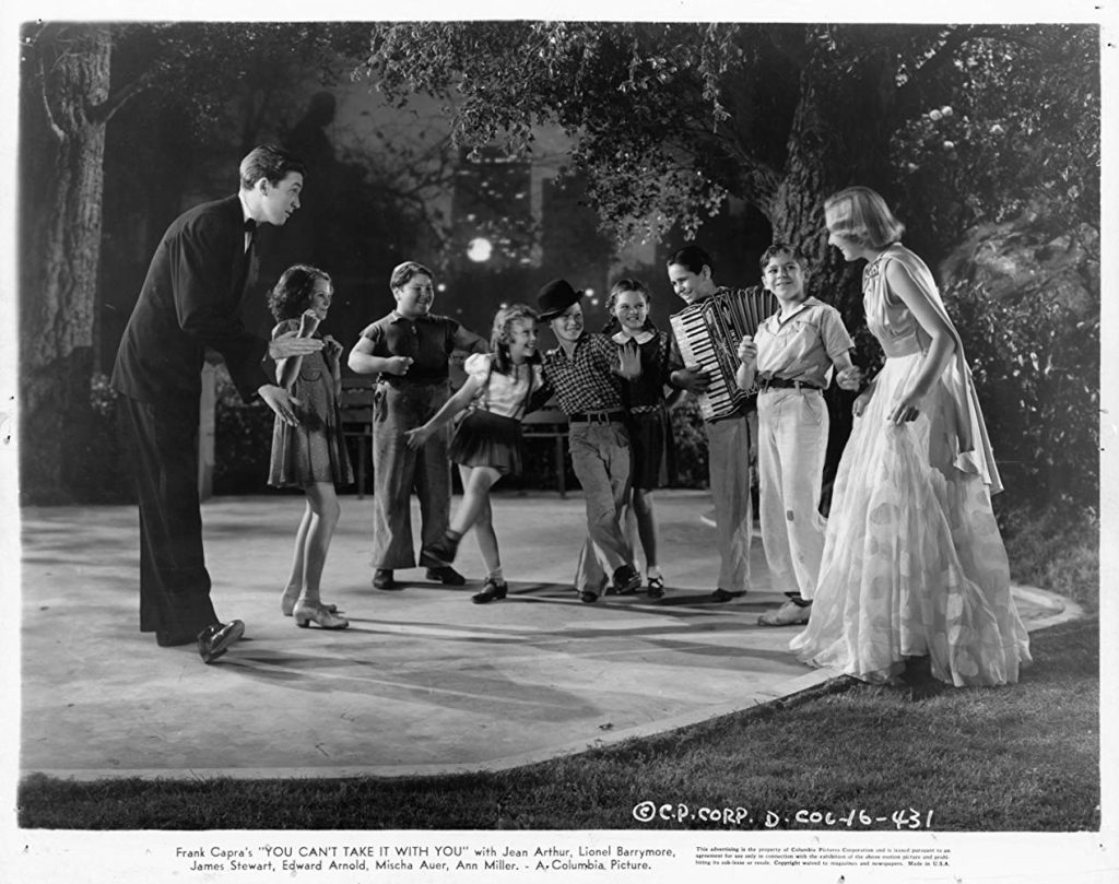 Escena en blanco y negro de Frank Capra dirigiendo a un grupo de actores en el set de Vive como quieras, película