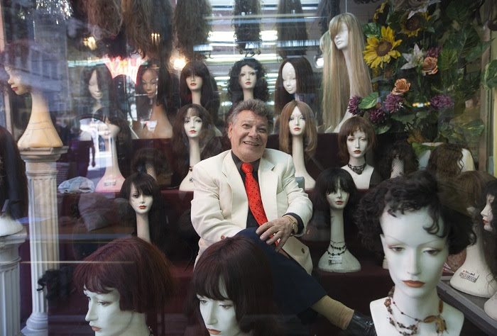 Documental "Il Siciliano": Fulgor y muerte del rey de las pelucas Hombre mayor con traje claro rodeado de maniquíes con pelucas y cabelleras en una tienda de accesorios capilares