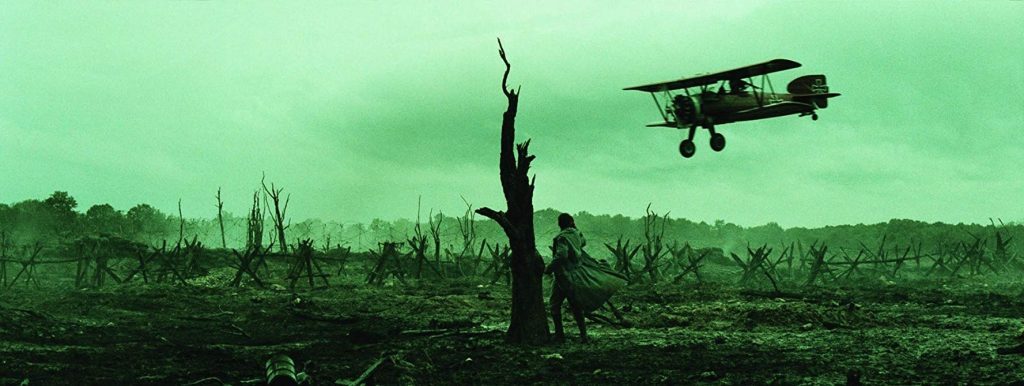 Paisaje desolado post-apocalíptico con ruinas de edificios destruidos, vegetación marchita y un biplano volando