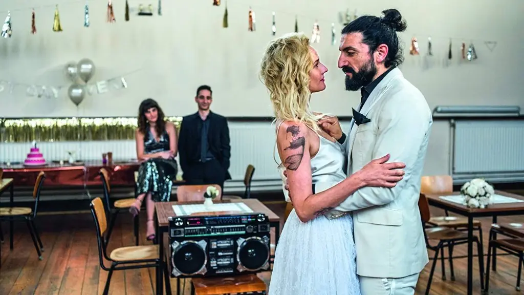 Pareja baila en sala de fiesta mientras otros observan; boombox retro en primer plano, decoración vintage