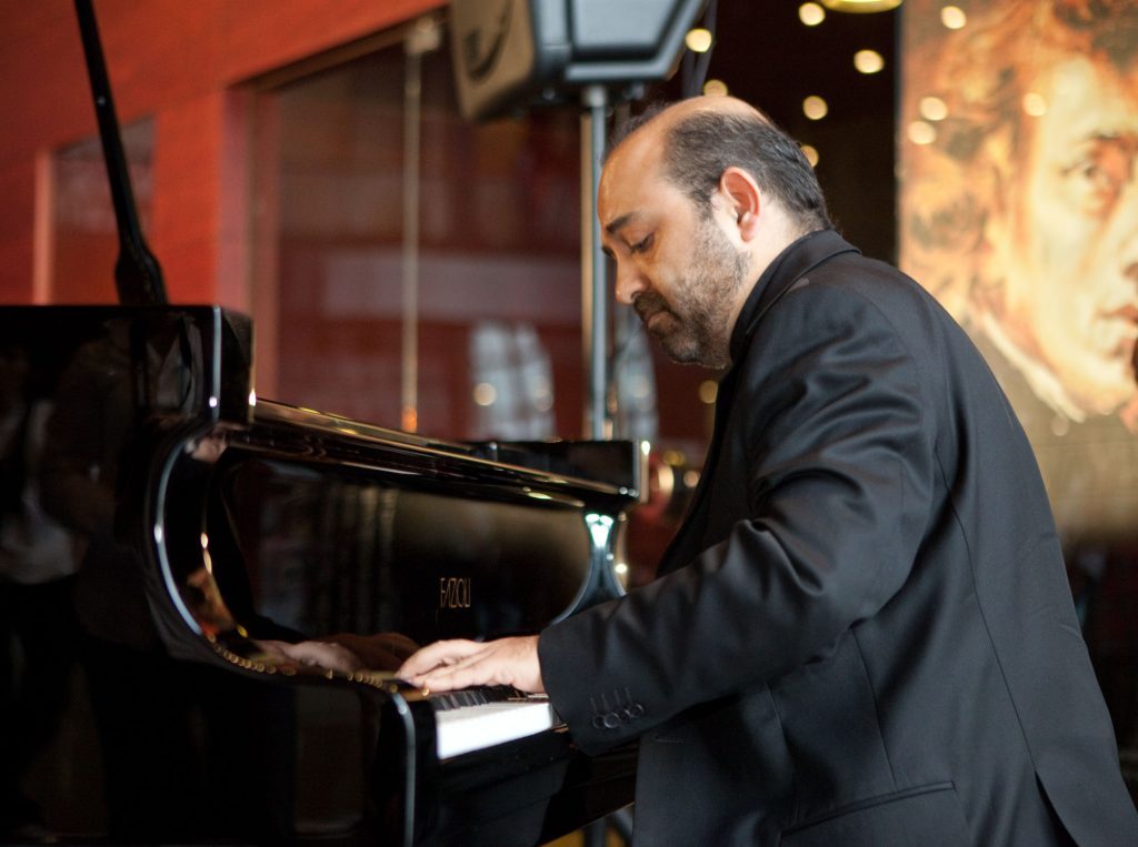 Pianista Alexandros Jusakos interpretando sonata de Beethoven en concierto, vestido con traje negro, concentrado
