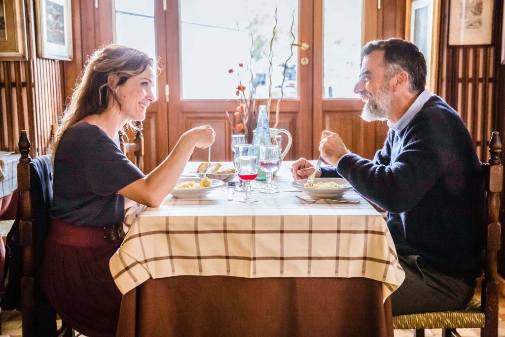 "Amores frágiles", de Francesca Comencini: La debilidad del guión Dos actores sentados a una mesa con mantel cuadriculado en una habitación de estilo clásico, en escena de conversación