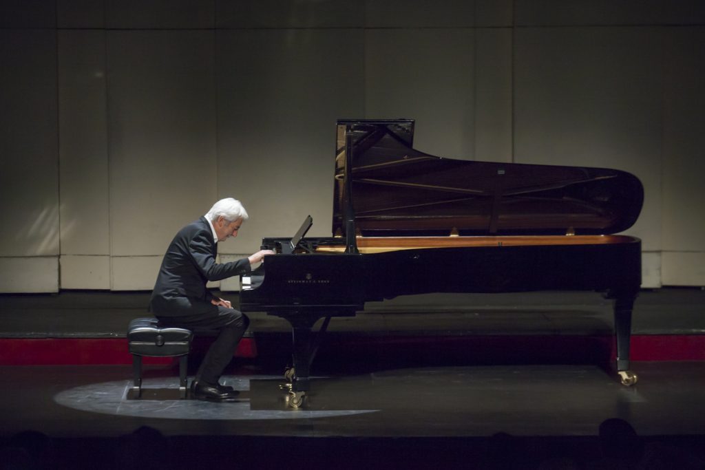 Pianista Jean-Philippe Collard toca un piano de cola negro en escenario del Teatro Municipal con iluminación teatral