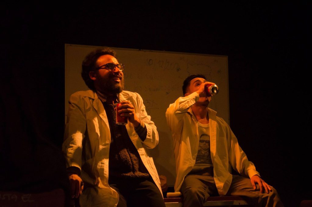 "La incógnita perdida", de Bastián Contreras: El último reducto de la Dictadura Tres actores en escena teatral iluminados en tonos cálidos, en poses dramáticas durante una representación teatral