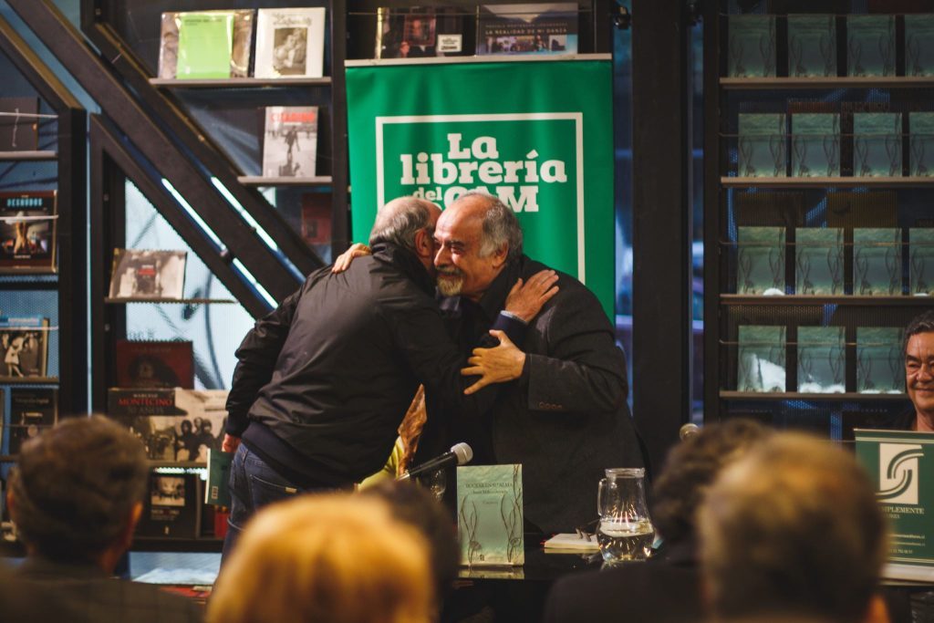Escritor Juan Mihovilovich durante presentación en librería, gesticulando mientras habla ante audiencia atenta
