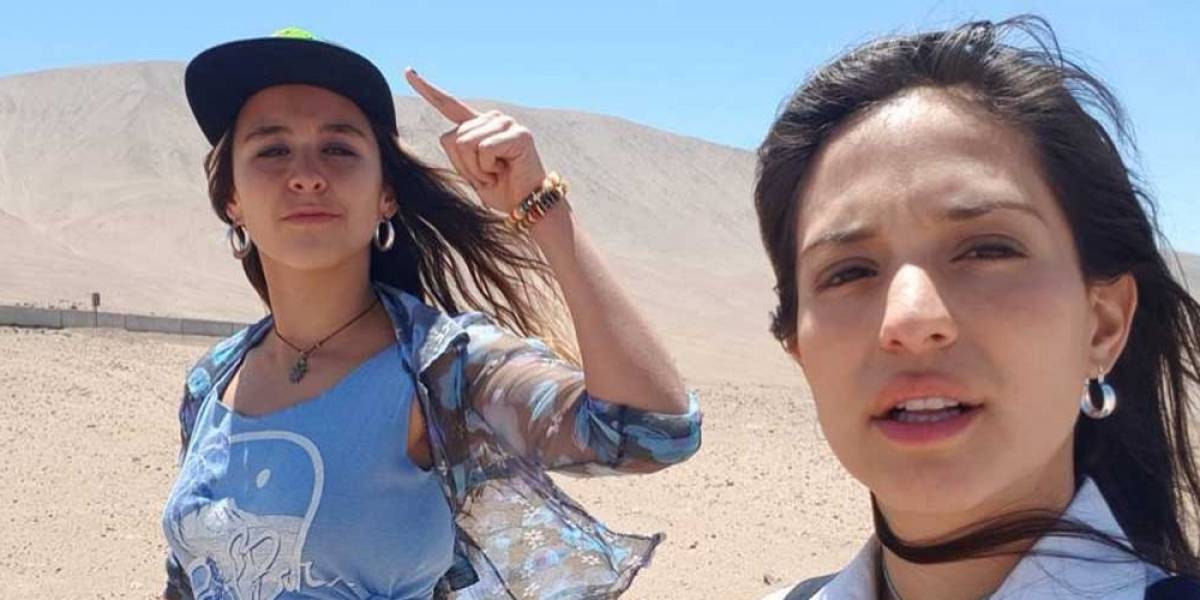 Serie “La cacería”: Réplicas de misoginia y de androcentrismo Dos mujeres en un desierto árido; una ajusta su gorro mientras la otra mira hacia la cámara bajo un cielo despejado