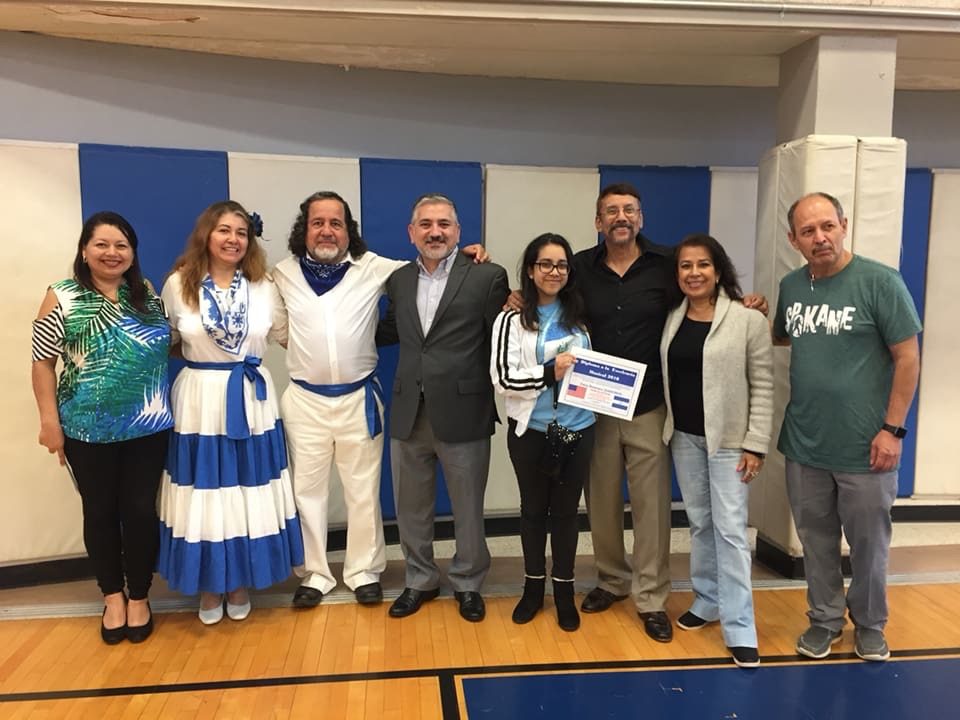 Grupo de nueve personas posando en escenario con diplomas durante acto de reconocimiento en festival de poesía