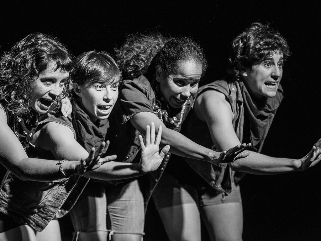 "Les Solidàries": La reivindicación feminista del panfleto Cuatro mujeres jóvenes en escena, con expresión intensa, extendiendo los brazos hacia adelante en gesto de protesta