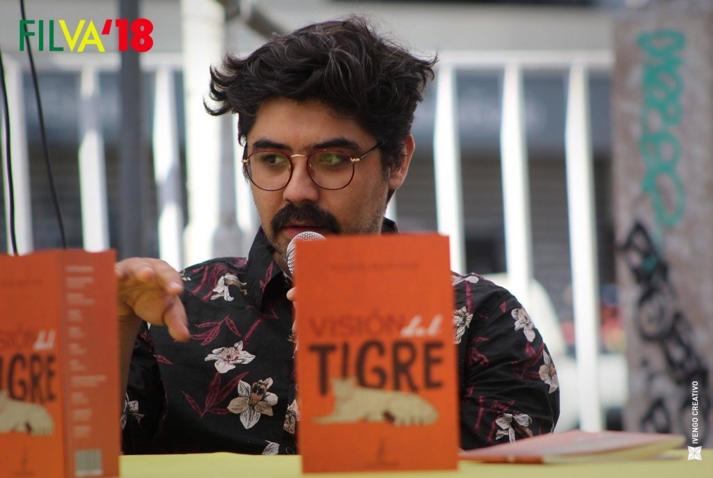 "Visión del tigre", de Nicolás Sepúlveda: El destino, siempre Nicolás Sepúlveda sostiene libros naranjas de su obra Visión del tigre, en ambiente de estudio