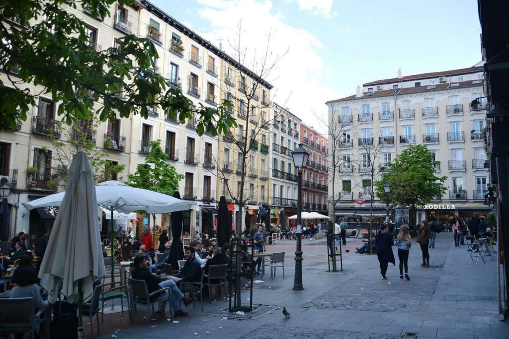 Plaza de Chueca en Madrid con terrazas, peatones y edificios históricos de fachada clásica bajo cielo despejado