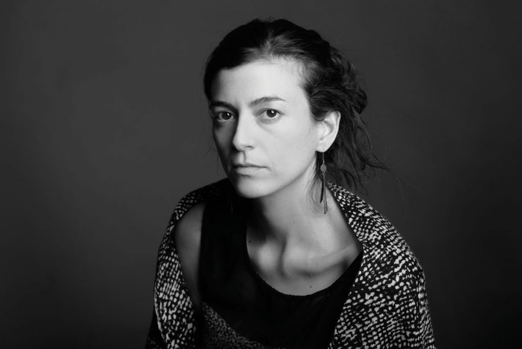 Retrato en blanco y negro de mujer con cabello largo, suéter texturizado y expresión seria mirando hacia un lado
