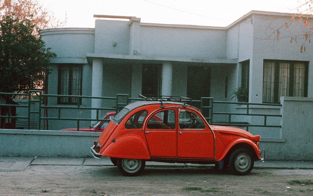 Fragmento de la novela "Años de fascinación", de Pascual Brodsky: El silencio de un tiempo extraño Auto Citroën rojo estacionado frente a edificio modernista de hormigón en barrio residencial