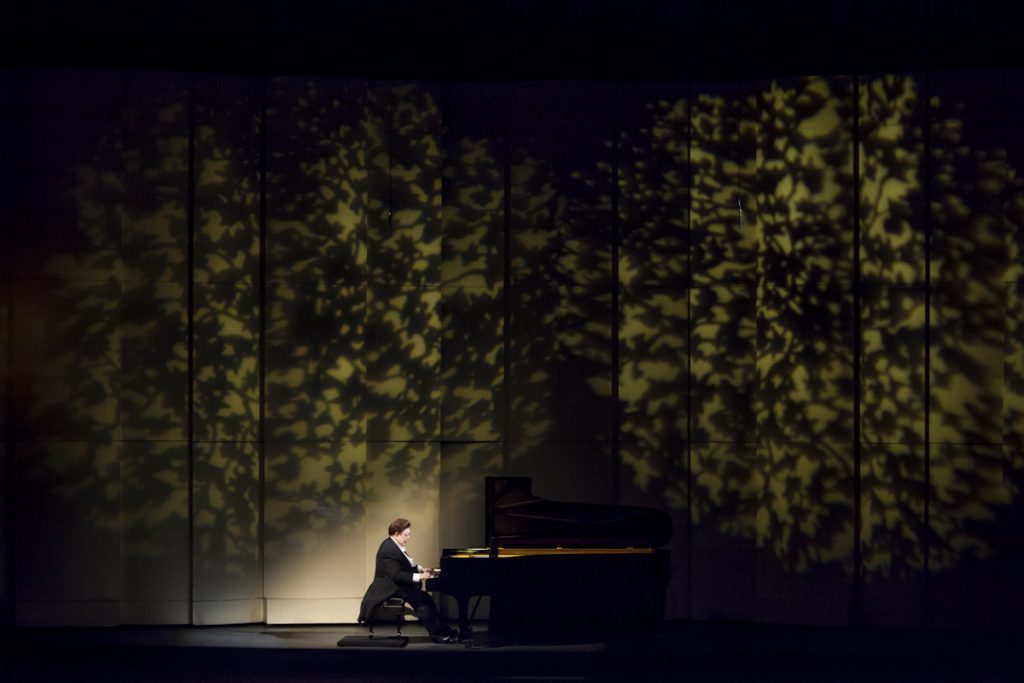 Pianista Bruno Gelber en el escenario del Teatro Municipal de Santiago, iluminado bajo decoración de enredaderas verdes