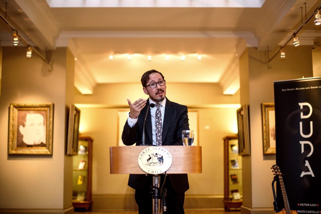 "Venga tu reino", de Víctor Ilich: No hay atajos para la verdad Víctor Ilich en podio durante presentación de libro, en sala con iluminación cálida y cuadros al fondo