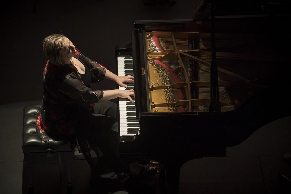 Pianista toca grand piano en escena iluminada, durante presentación del Ciclo de Pianistas Ceac 2019 en el GAM