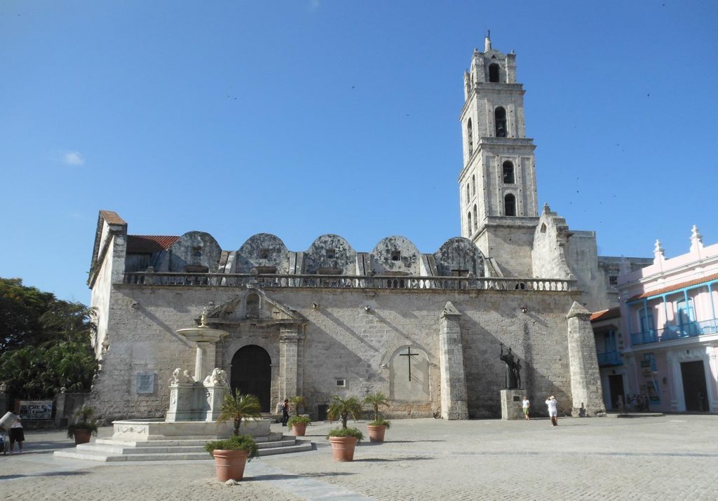 Iglesia colonial con torre blanca en plaza de La Habana, arquitectura religiosa cubana de fachada neoclásica