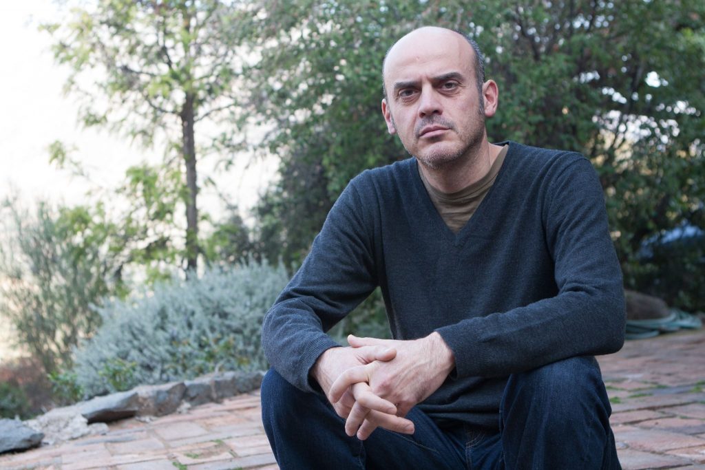 "Entremuros", de Sergio Missana: La idea de una novela total Sergio Missana, autor chileno, posando en un jardín con árboles de fondo, mirando hacia la cámara con expresión seria