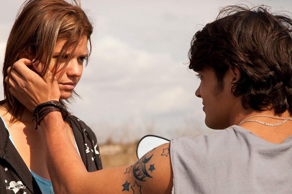 "Esto no es Quinto Medio": Un cuento de inquietante actualidad Dos jóvenes en conversación íntima al aire libre, ella con tatuaje visible en el brazo, cielo nublado de fondo