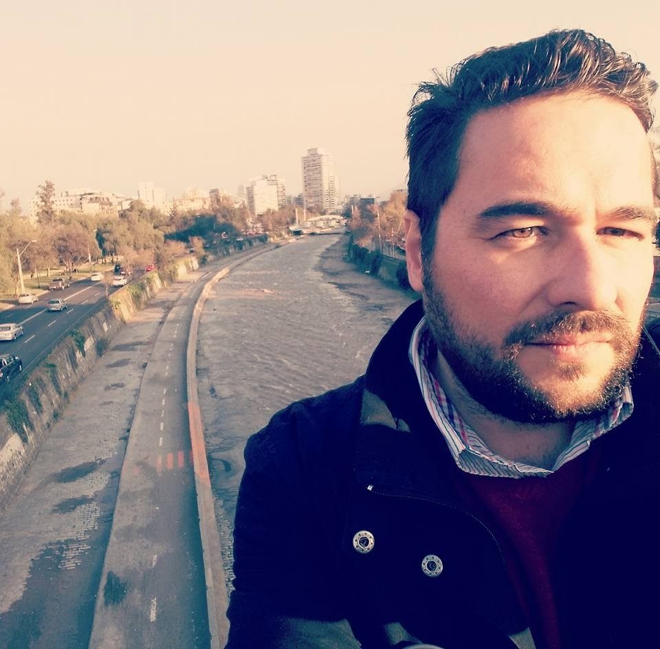 Ernesto González Barnert en selfie con vías de tren y skyline urbano de fondo al atardecer