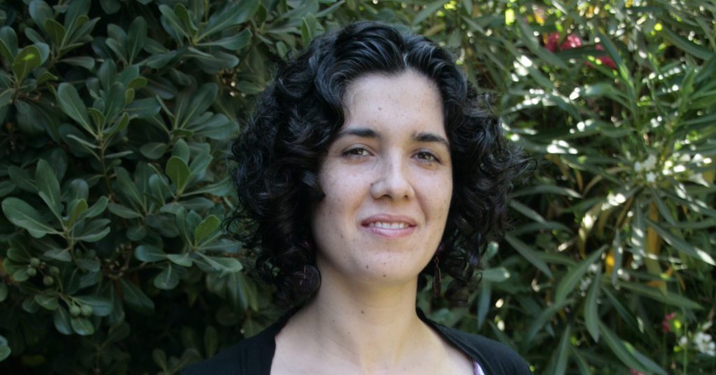 Constanza Anabalón Tohá, escritora chilena, retratada ante un fondo de vegetación verde