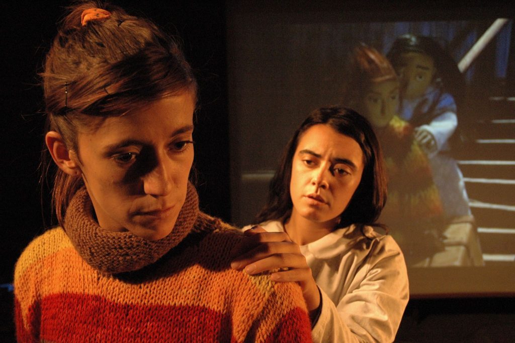 «Maleza»: Teatro-animación pionero en Chile Dos actores en escena de teatro-animación: mujer con suéter naranja en primer plano y hombre de cabello largo detrás