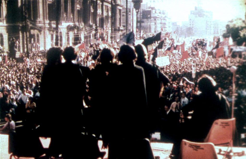 Multitud congregada en concentración política de 1973 en Chile, con oradores en tarima ante miles de personas en plaza