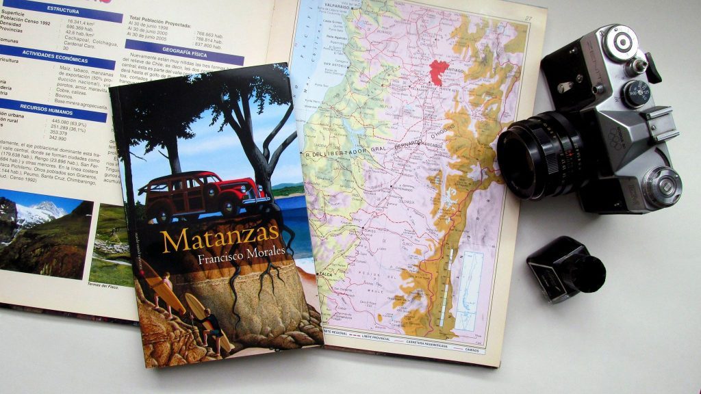 Portada del libro Matanzas junto a una cámara vintage, mapa geográfico y fotografías de referencia sobre una superficie