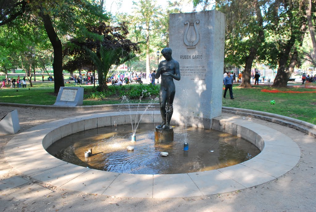 Monumento a Rubén Darío en parque público con escultura de bronce del poeta, fuente circular y árboles de fondo