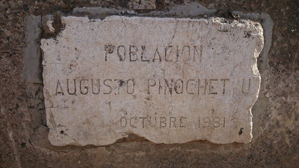Placa de cementerio con inscripción Población Augusto Pinochet, octubre 1973, sobre piedra desgastada