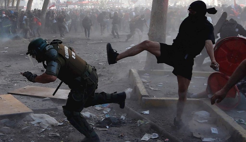 Manifestante en confrontación con fuerzas de seguridad durante protestas callejeras con gases lacrimógenos y caos urbano