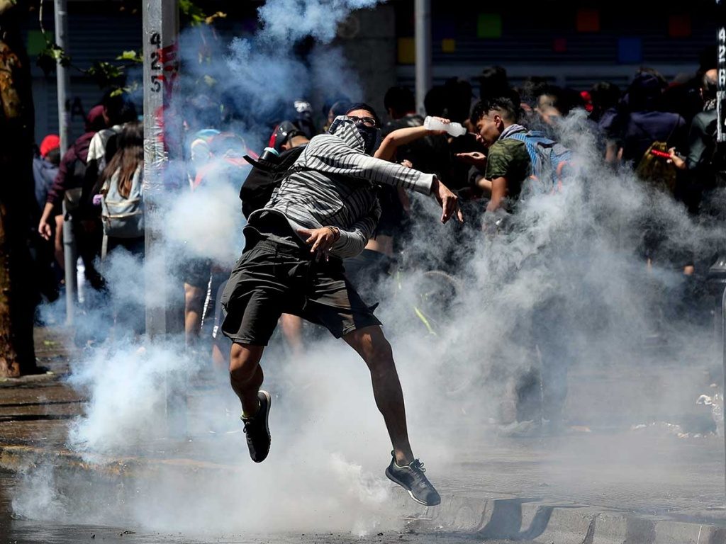 ¿Y qué pasa con la cultura?: Una reflexión sobre la esencia de la Revolución de Octubre Chilena Manifestante salta entre nubes de gas lacrimógeno durante protesta en Chile, capturado en medio de la confrontación
