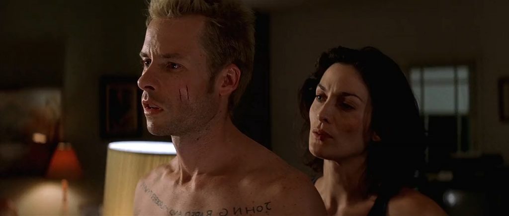 "Memento", de Christopher Nolan: El deber de recordar Hombre sin camisa y mujer en intensa conversación nocturna en habitación con luz tenue