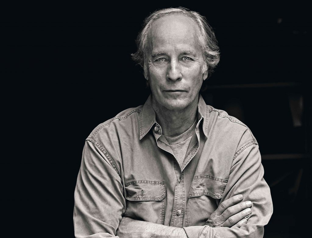 Los cuentos de "Lamento lo ocurrido", de Richard Ford: La rabia del silencio Richard Ford, escritor estadounidense, retrato en blanco y negro con brazos cruzados y fondo oscuro
