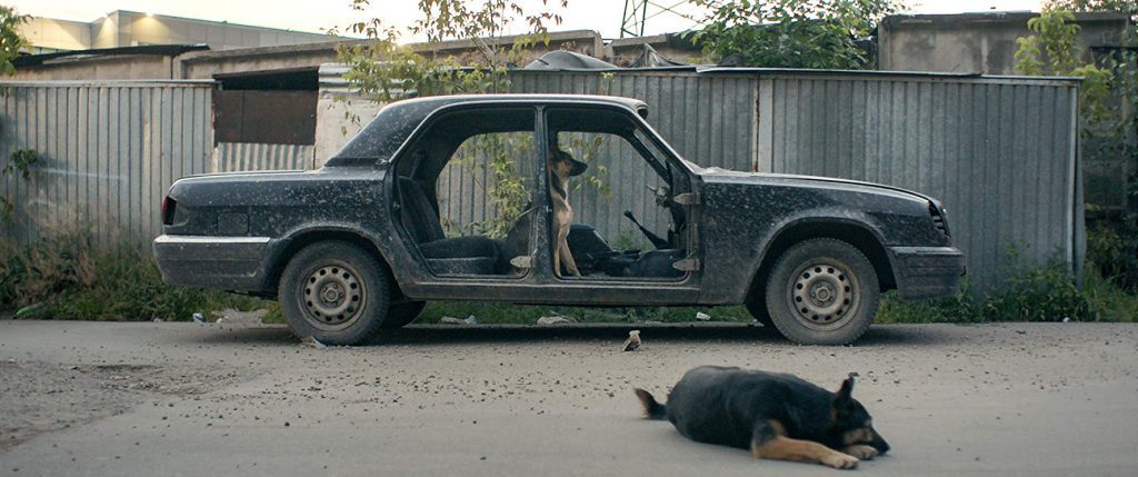 Fidocs 2019: "Space Dogs", cuestión de perspectiva Auto abandonado con puerta abierta y figura tendida en el suelo en escena de drama cinematográfico