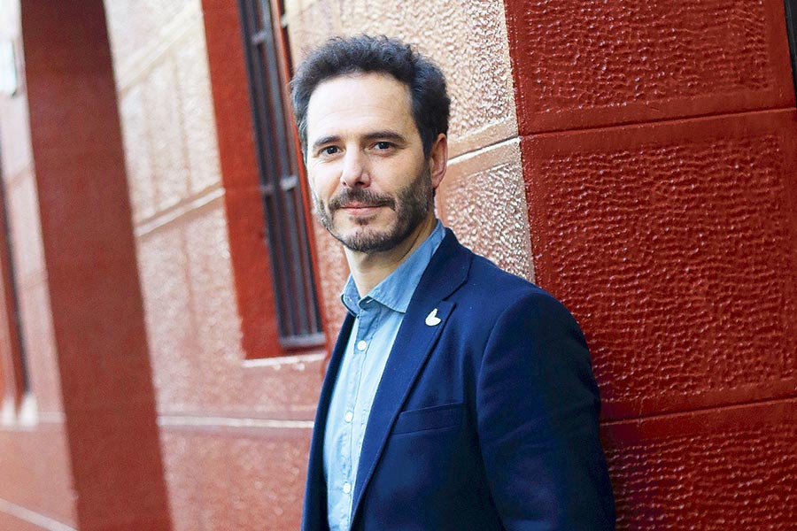 Hernán Larraín Matte, político chileno, posando frente a pared de ladrillo rojo con blazer azul marino